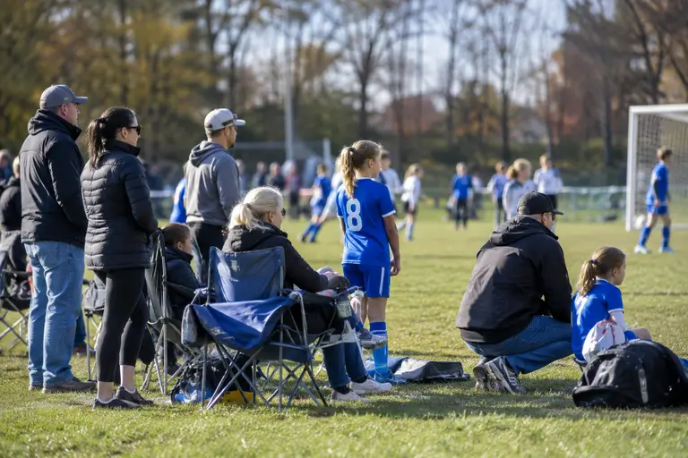 Families and coaches gather near a youth soccer field on matchday
